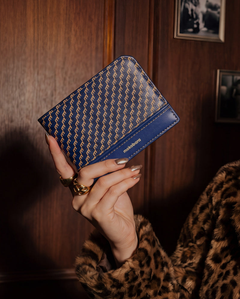 Navy Stash Bifold Wallet held up in a wood-panelled room