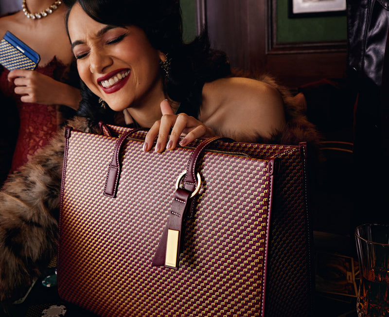 Woman laughing as she reaches into a maroon Skye Tote