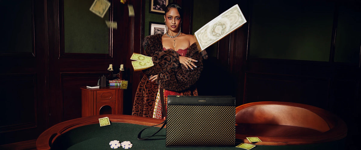 A woman in a leopard fur stole tosses banknotes behind a black Freddie’s Pouch on a card table